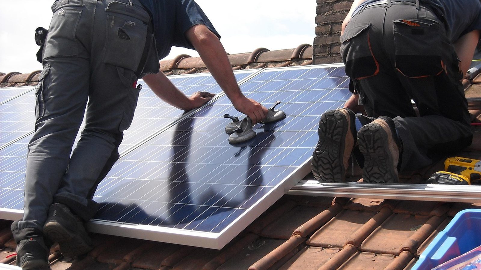 Workers placing solar panels on a residential roof