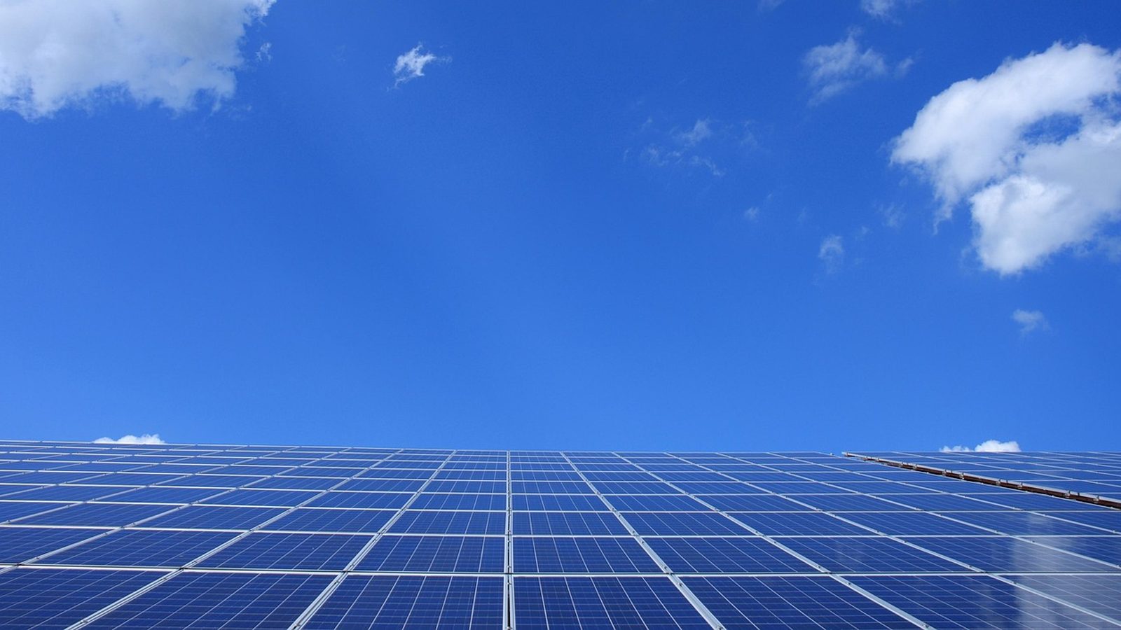 Rows of photovoltaic modules under a partly cloudy sky