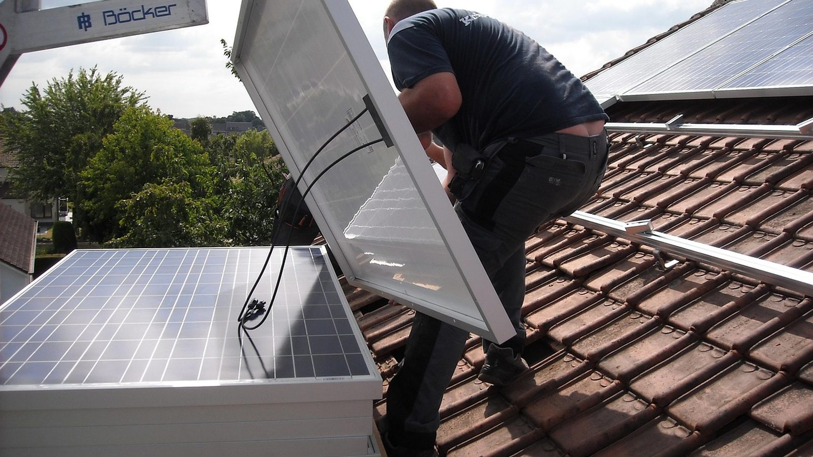 Installer placing solar panels on a tiled roof