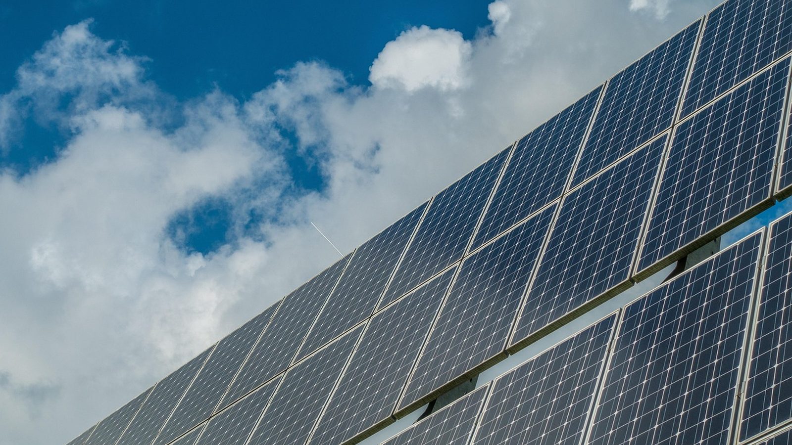 Photovoltaic modules in rows under a partly cloudy sky