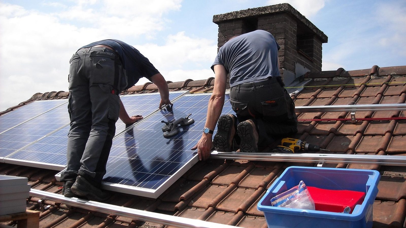 Workers placing solar panels on a residential roof