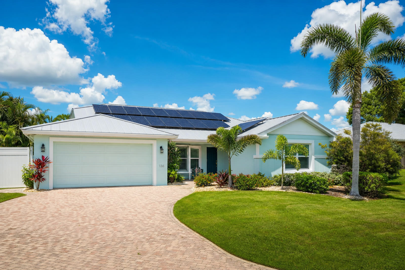 Florida stucco home with tile roof and solar panels framed by palm trees